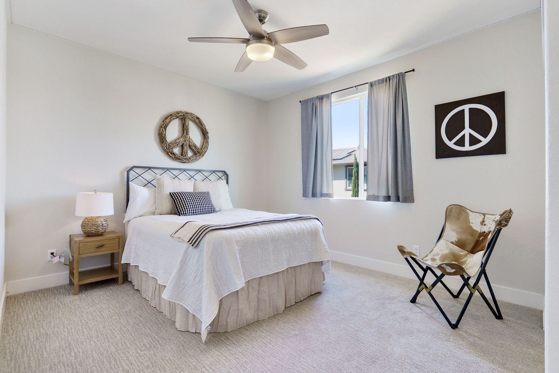 Bedroom with a bed, nightstand, chair, peace sign decor, and a window.
