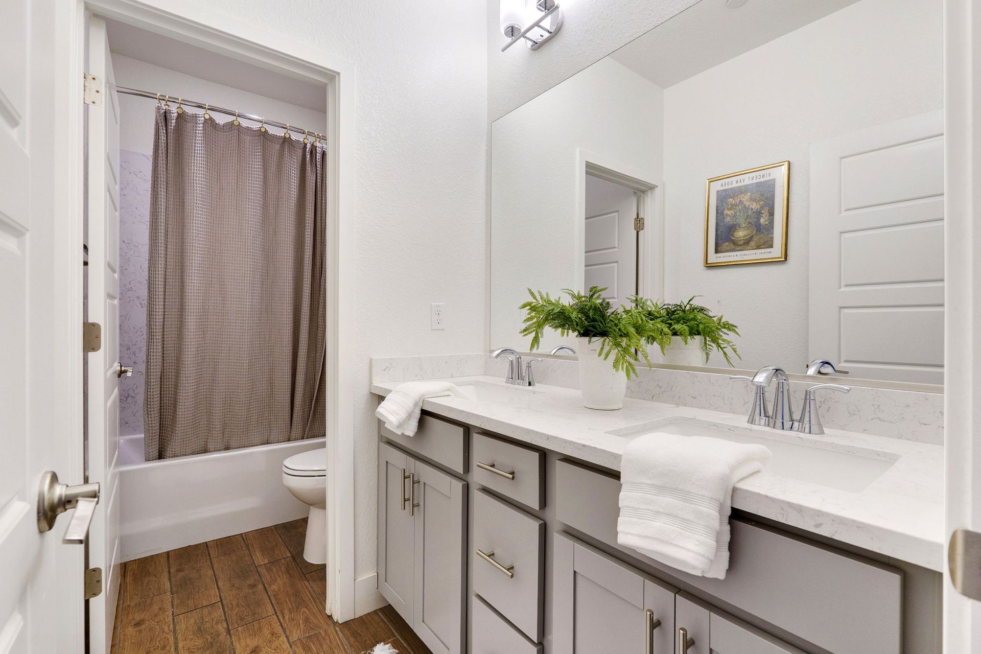 Bathroom with gray vanity, white countertop, and doorway to a tub with shower curtain.