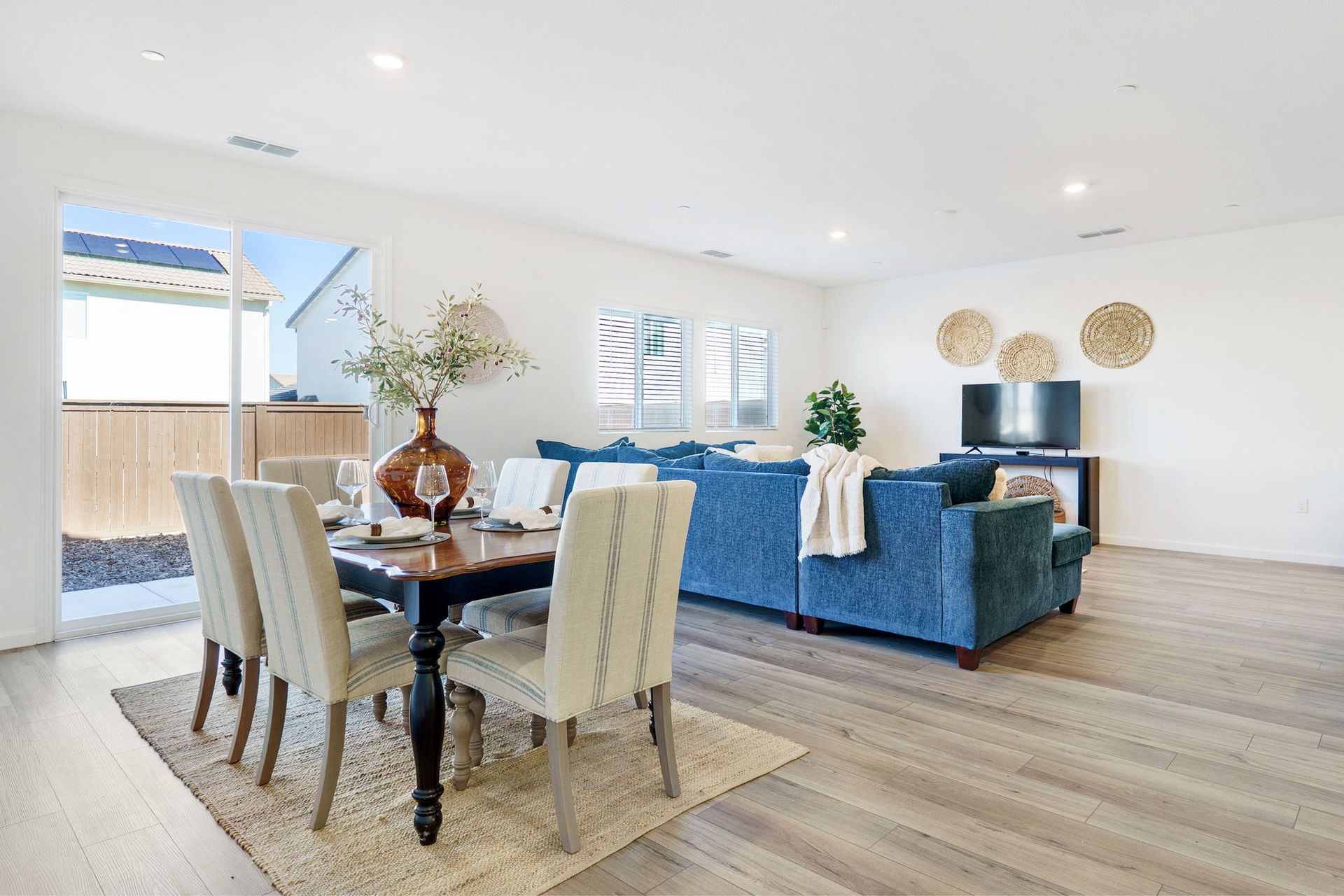 Open-concept living space with a dining area, a blue sofa, and a television.