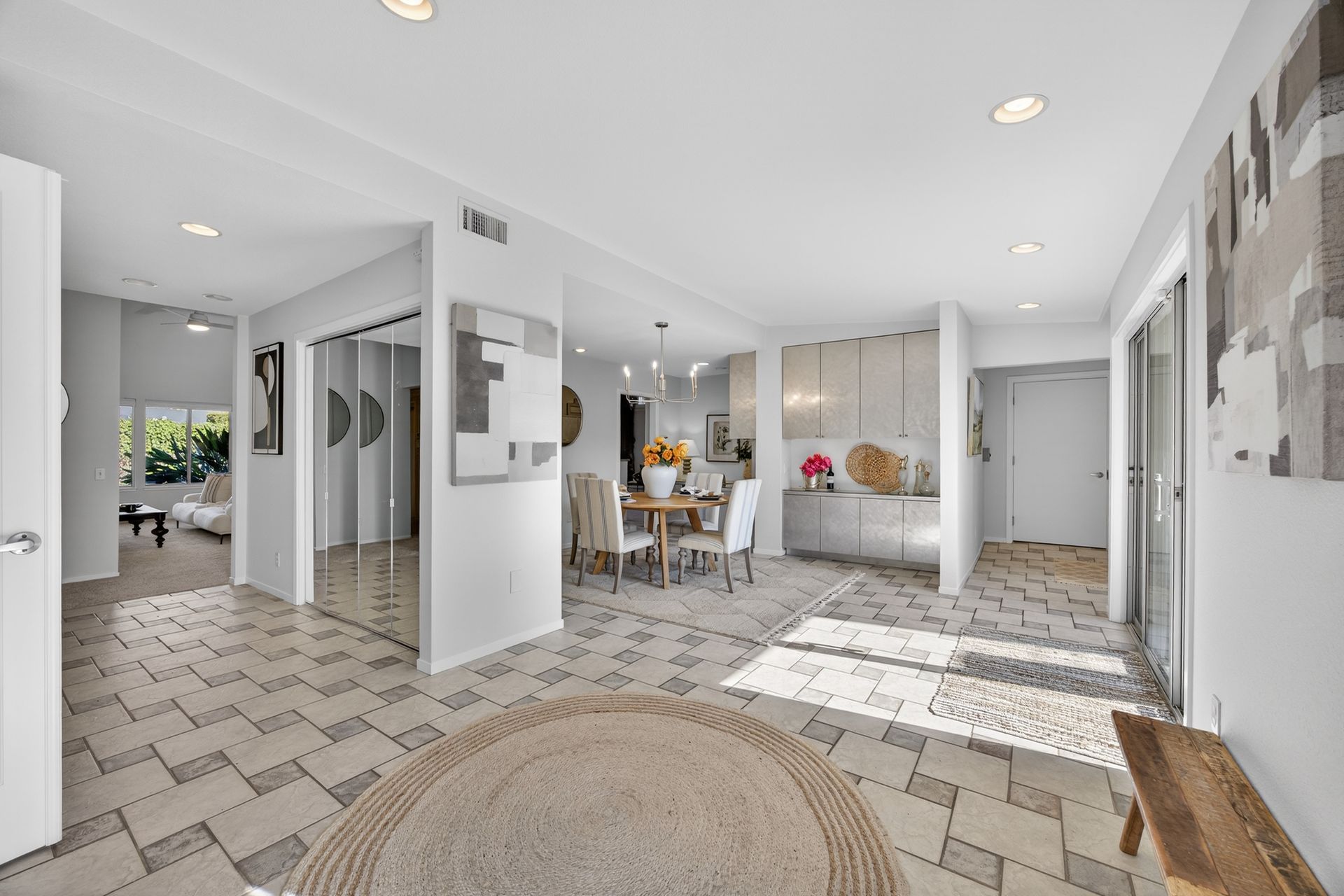 Spacious, bright interior with dining area and entry hall. White and beige tones, tiled flooring.