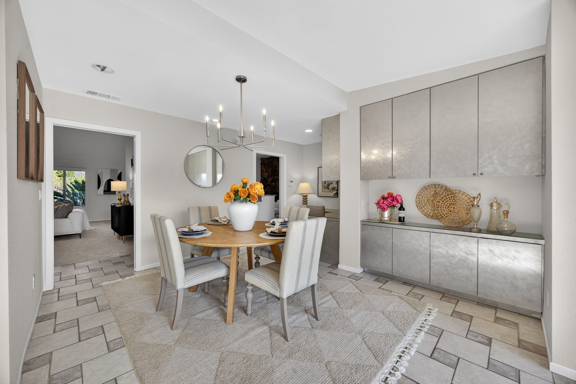 Dining room with round wooden table, chairs, and ornate chandelier. Built-in storage against the wall.