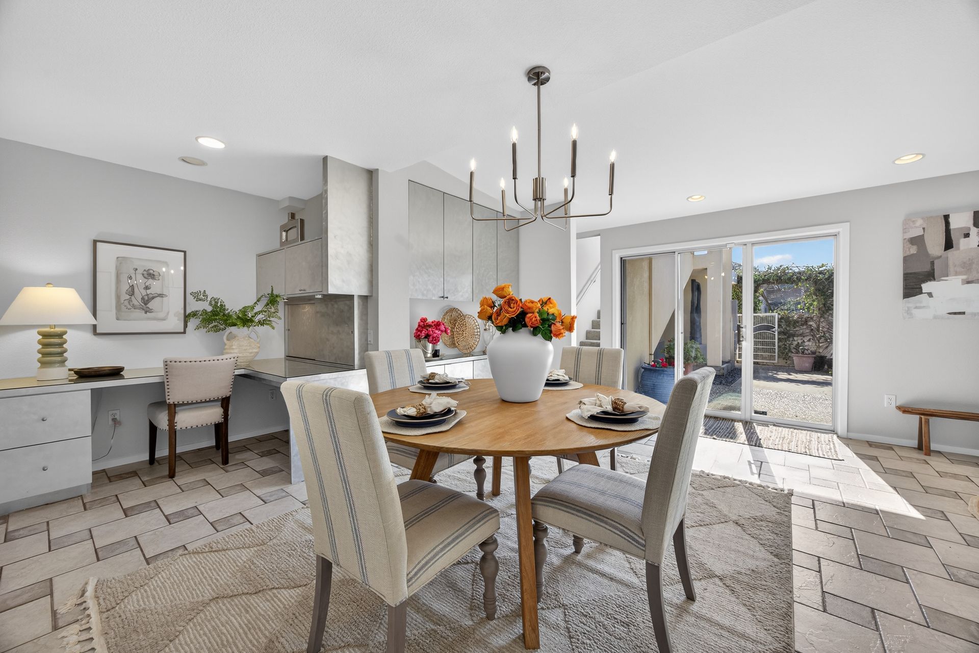 Dining room with round wooden table, chairs, and flowers. Sliding glass door leads to patio.