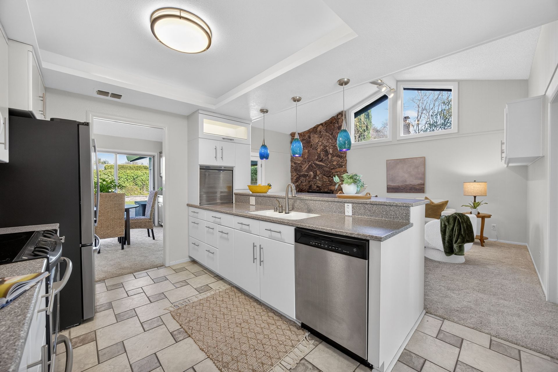 Modern kitchen with white cabinets, stainless steel appliances, and a pass-through to a dining area.