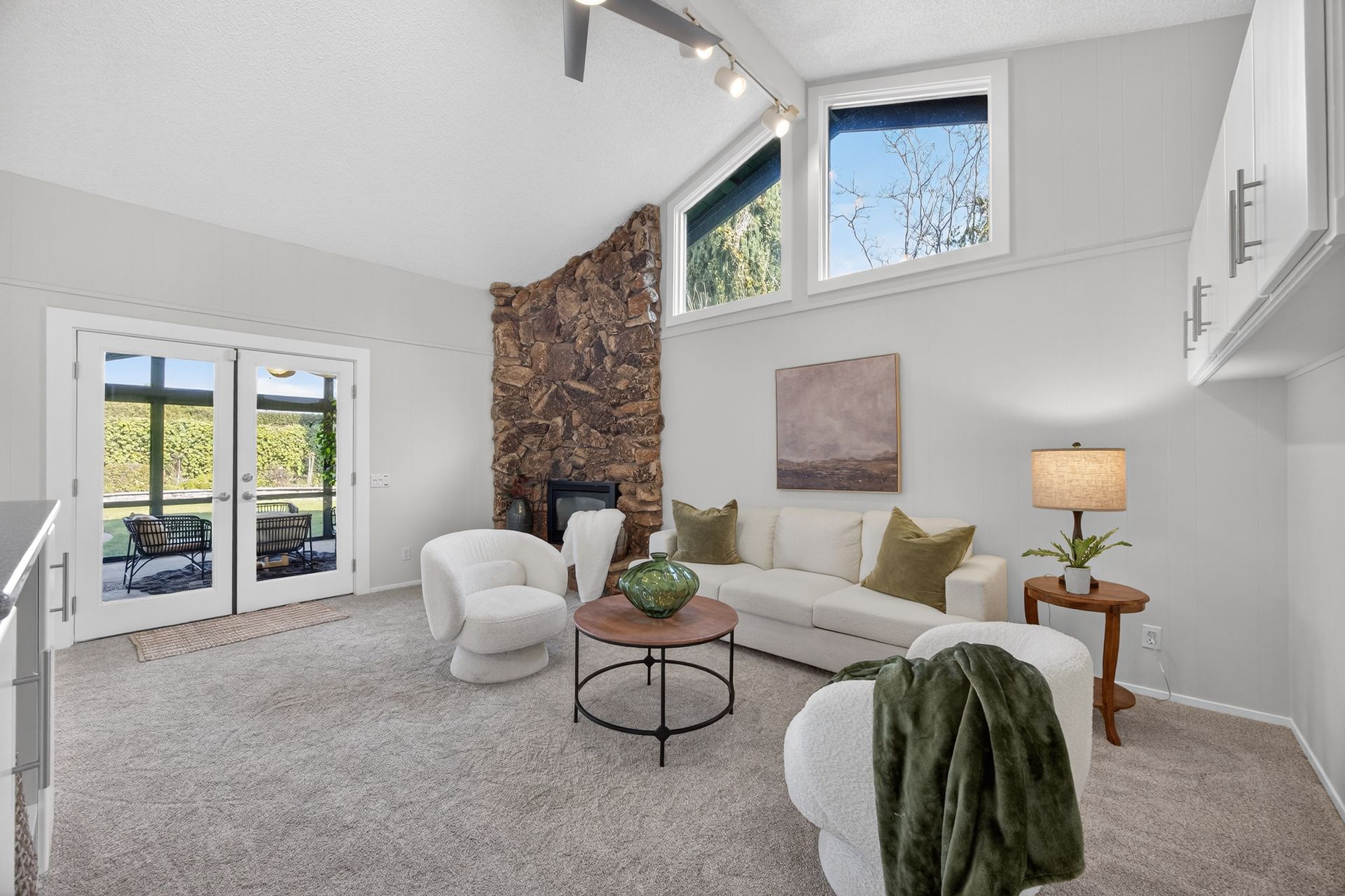 Living room with stone fireplace, white sofa, and armchairs, natural light.