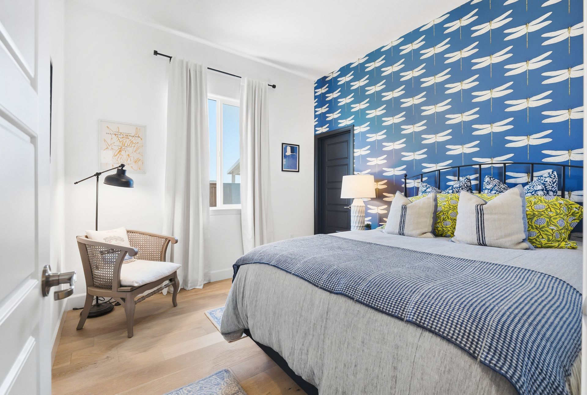 Bedroom with blue patterned accent wall, bed, chair, and window.