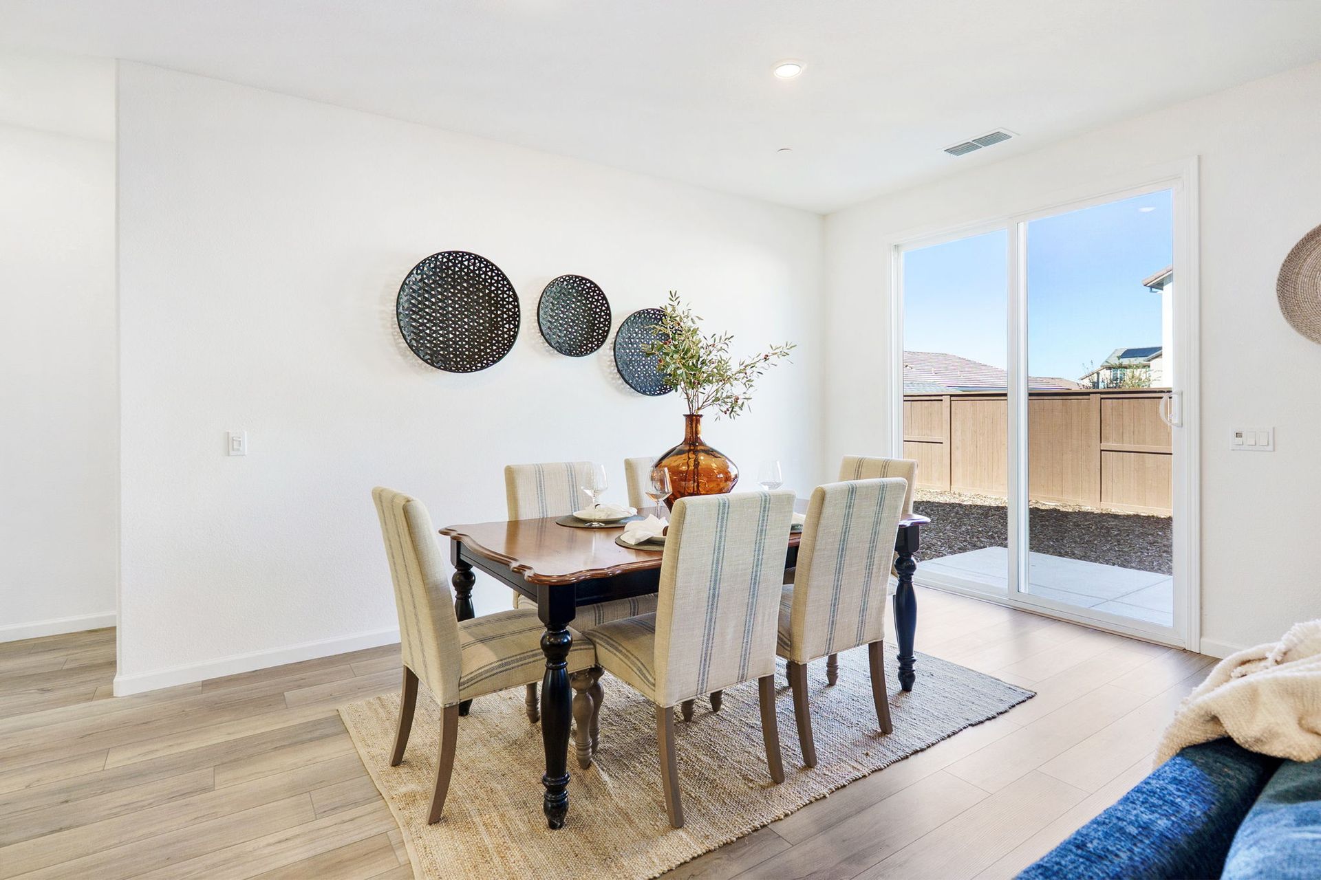 Dining room with table, chairs, decor, and sliding door. Light wood flooring and neutral walls.