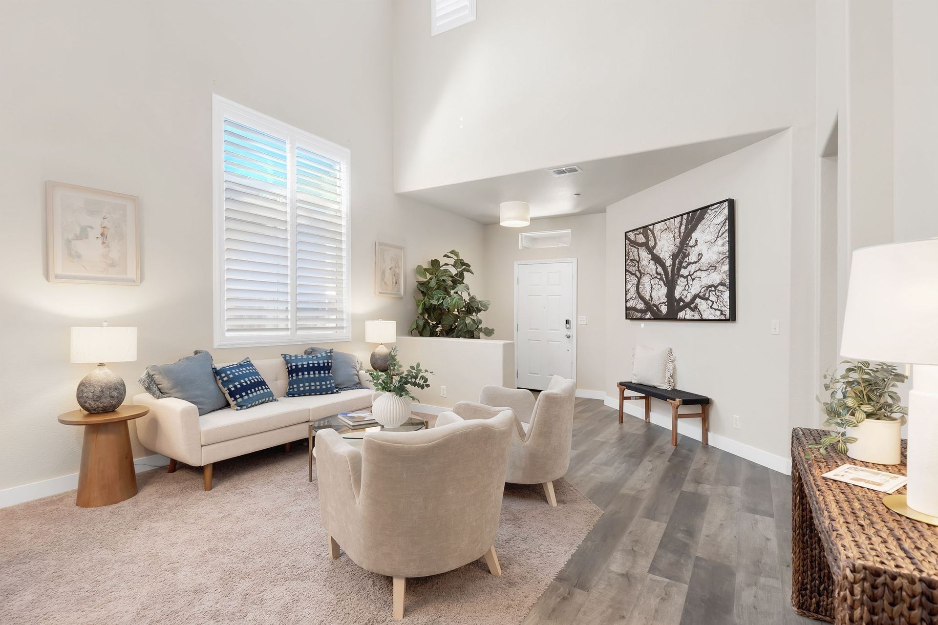 Living room with white walls, beige furniture, rug, and hardwood flooring.