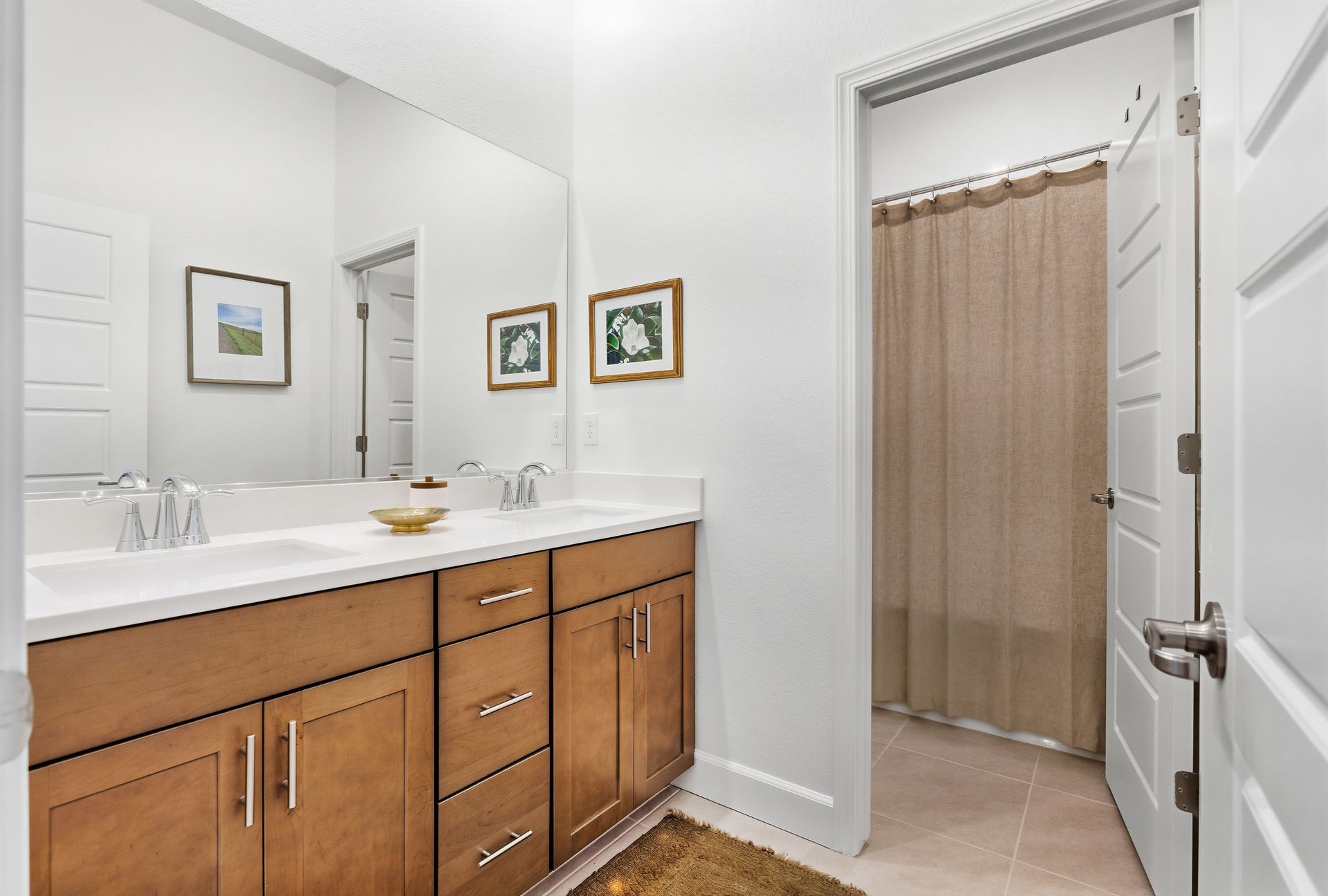 Bathroom with brown vanity, white countertop, and doorway to a shower with a tan curtain.