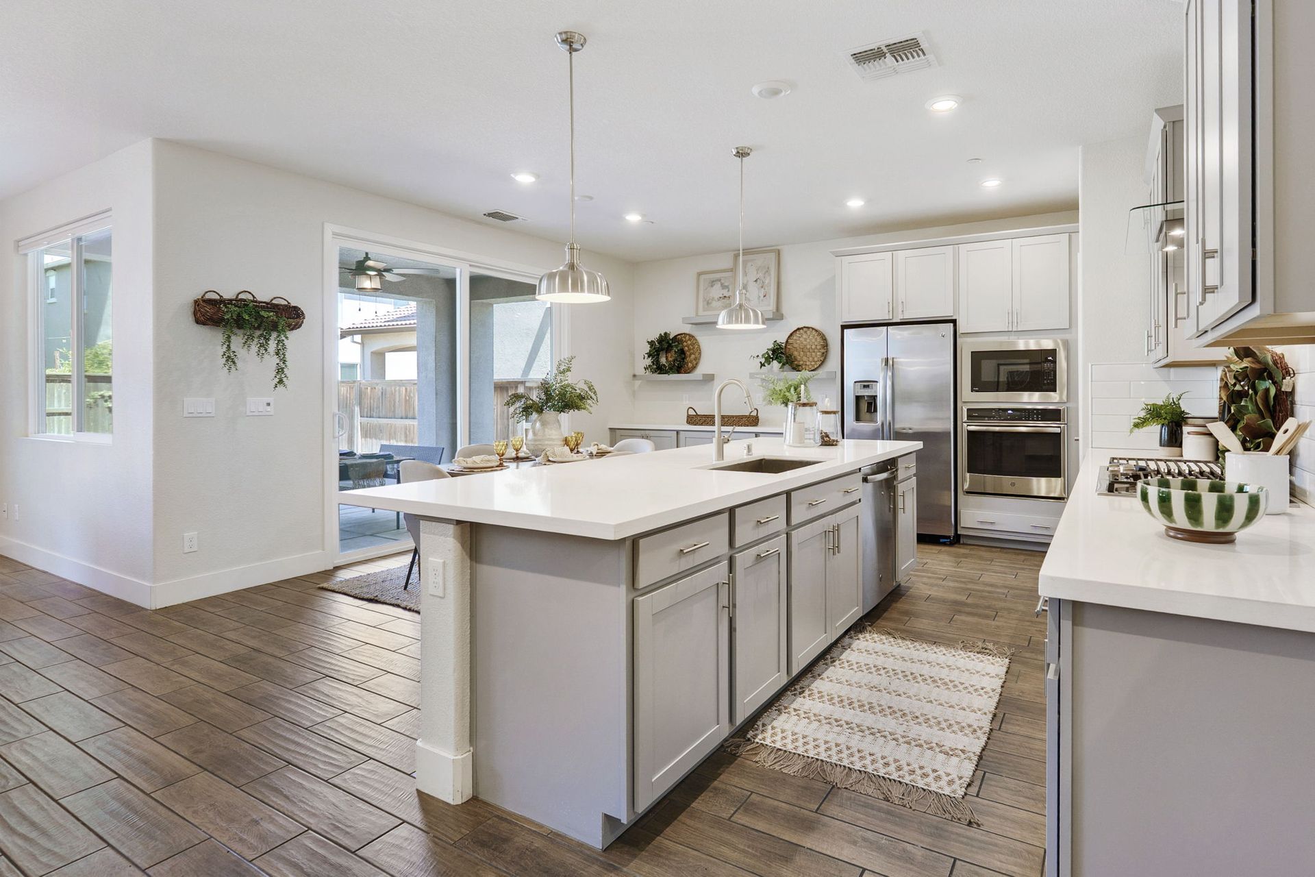 Spacious modern kitchen with island, stainless steel appliances, and sliding glass door to patio.