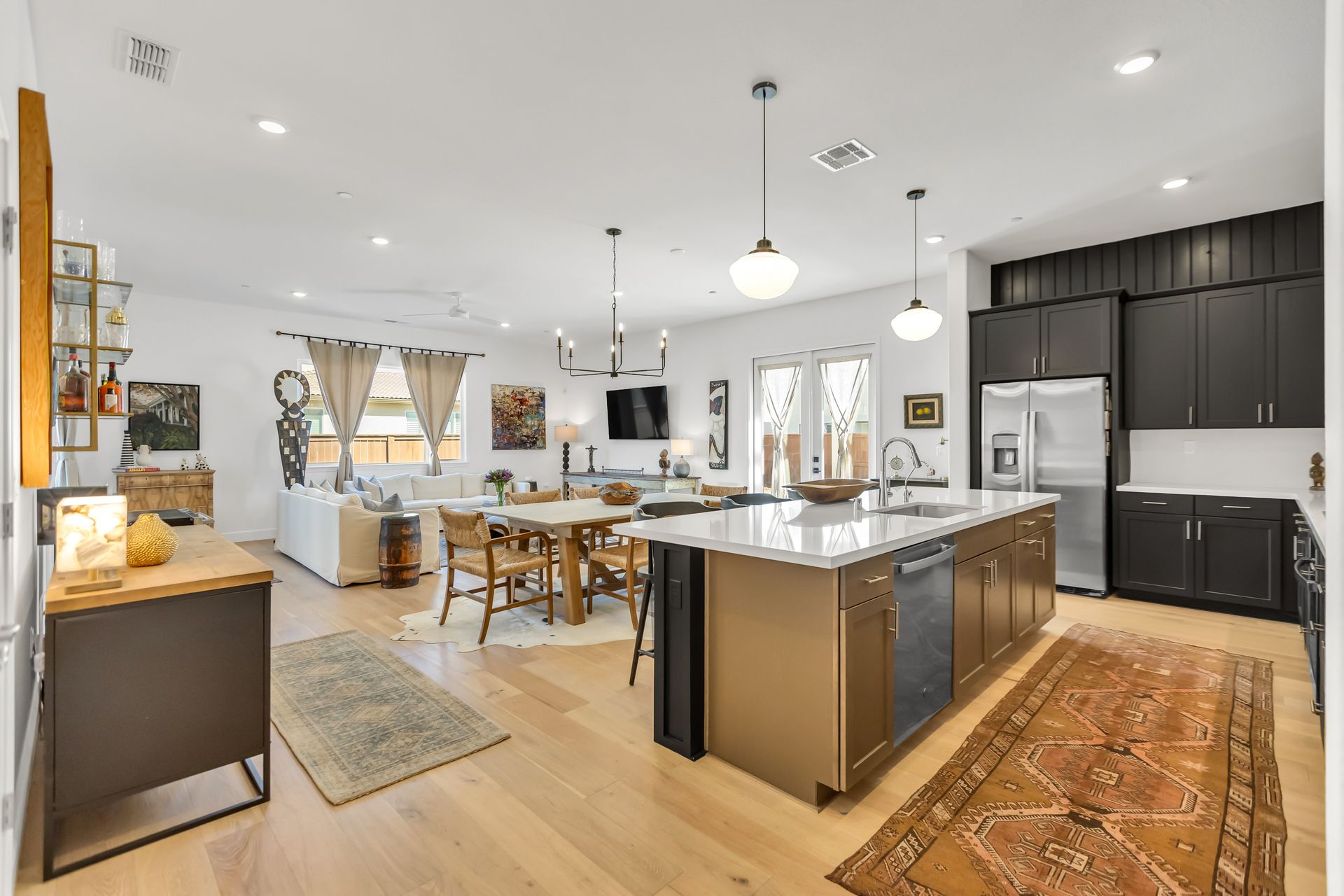 Open-concept kitchen and living area with wood floors, island, and dark cabinets.