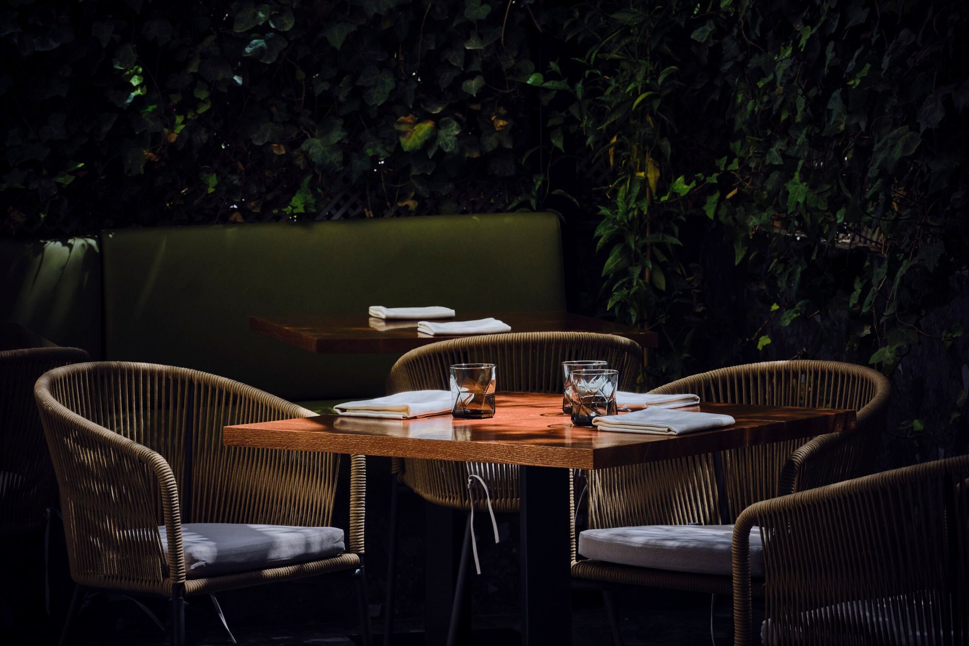 A table with chairs and glasses on it in a dark room.