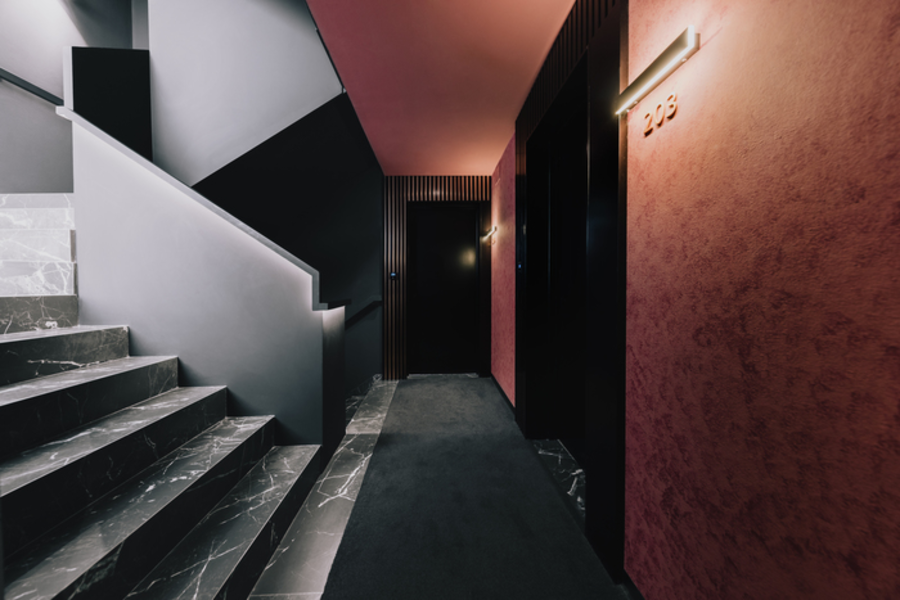 A hallway with stairs and a door in a building.