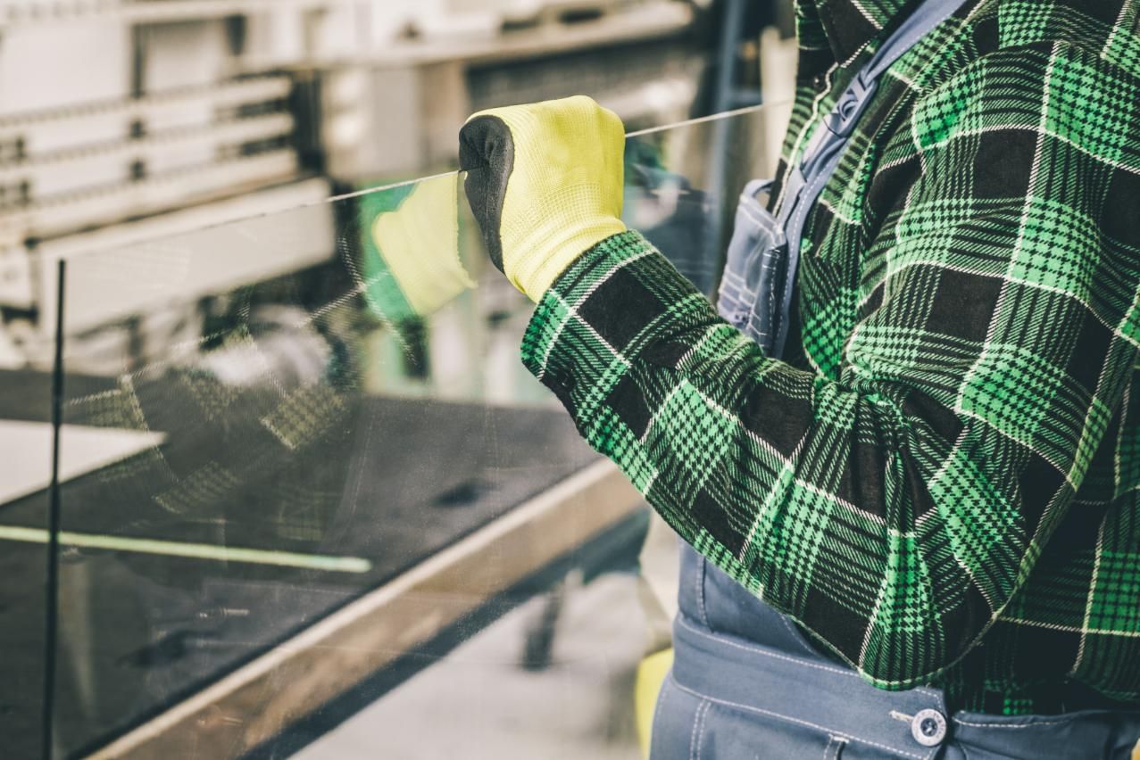 Man in a Plaid Shirt and Yellow Gloves is Cutting a Piece of Glass — Glass & Window Centre, Dubbo, NSW