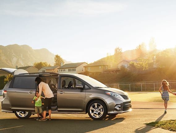 Una mujer y dos niños bajan de una minivan.