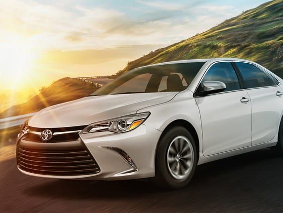 Un Toyota Camry blanco está estacionado al costado de una carretera.