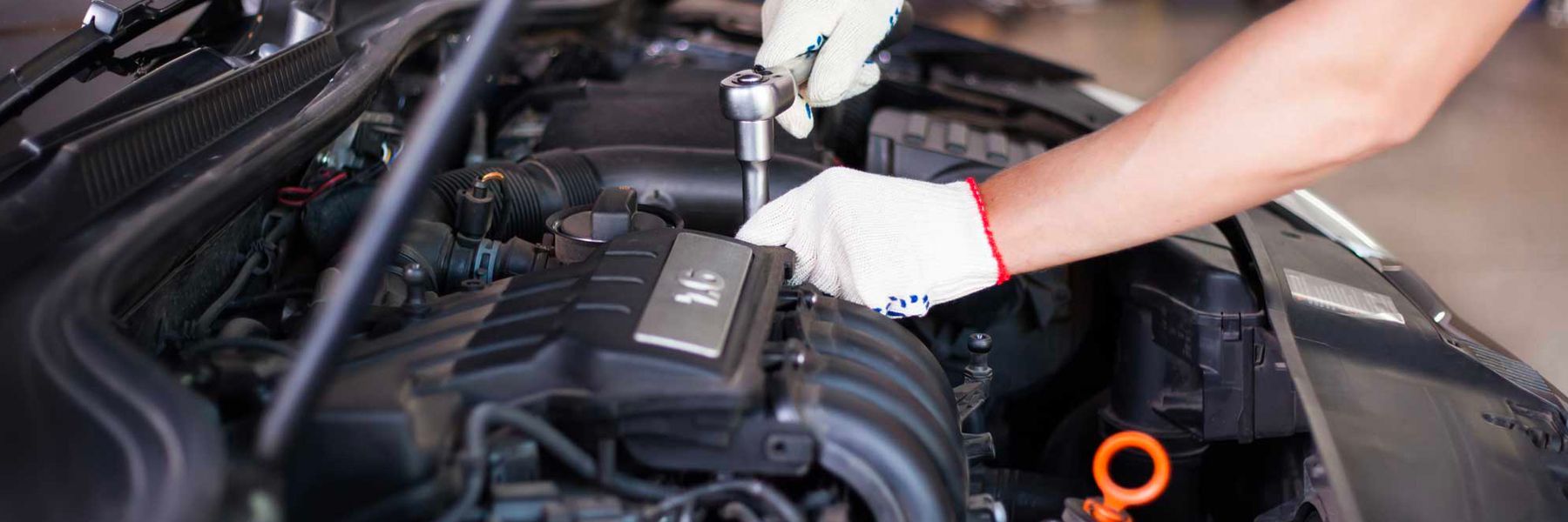 A man is working on the engine of a car with a wrench.