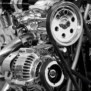 A close up of a car engine with a belt and alternator.