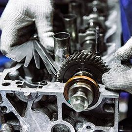 A close up of a person working on a car engine.