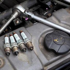 A close up of a car engine with spark plugs and a wrench.