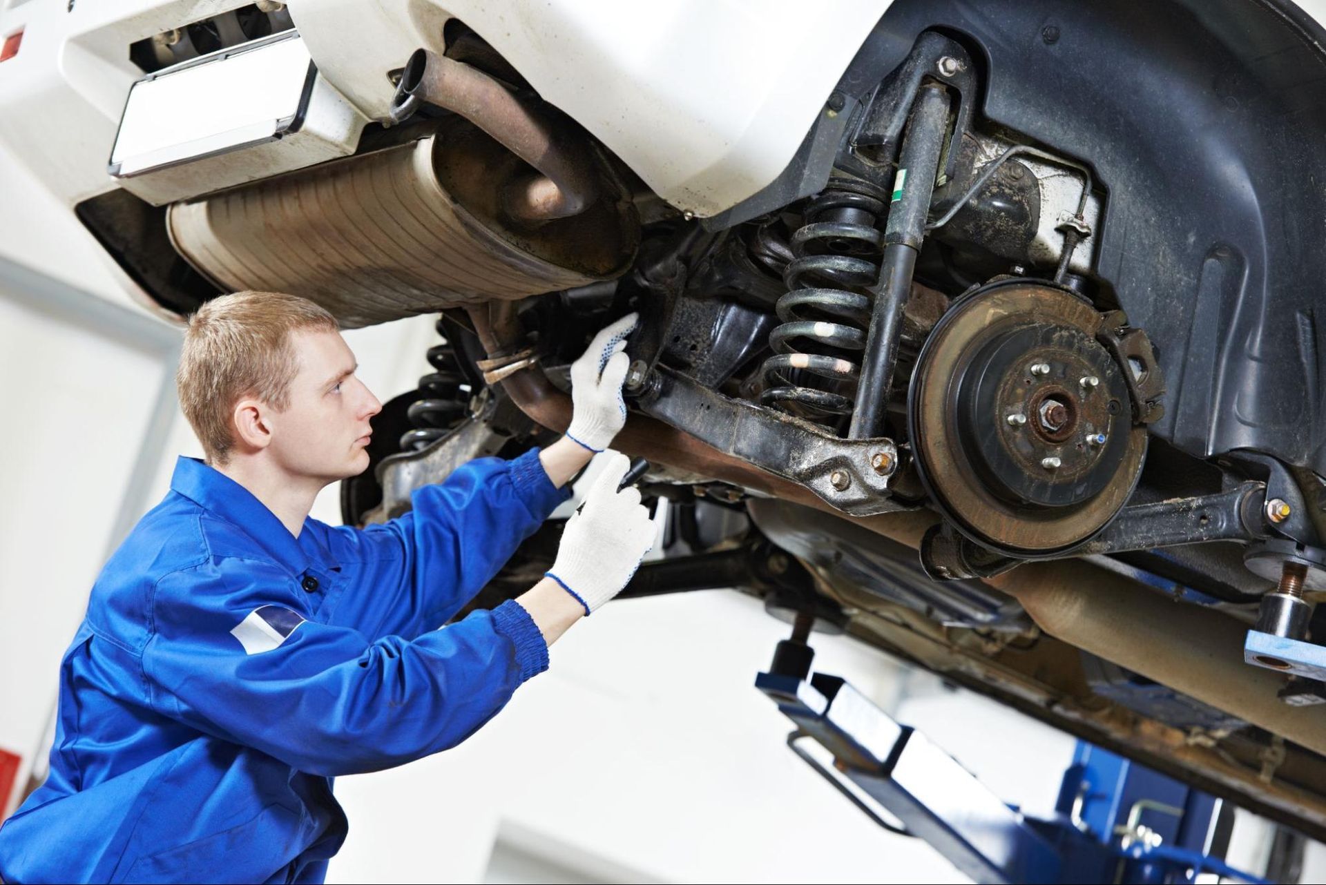 A man is working on the underside of a car in a garage.