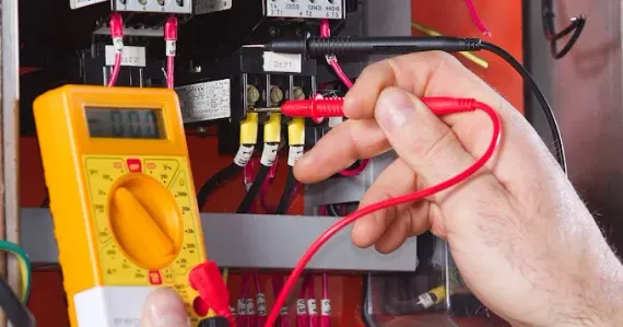 Black pipes and fittings attached to a light-colored brick building.