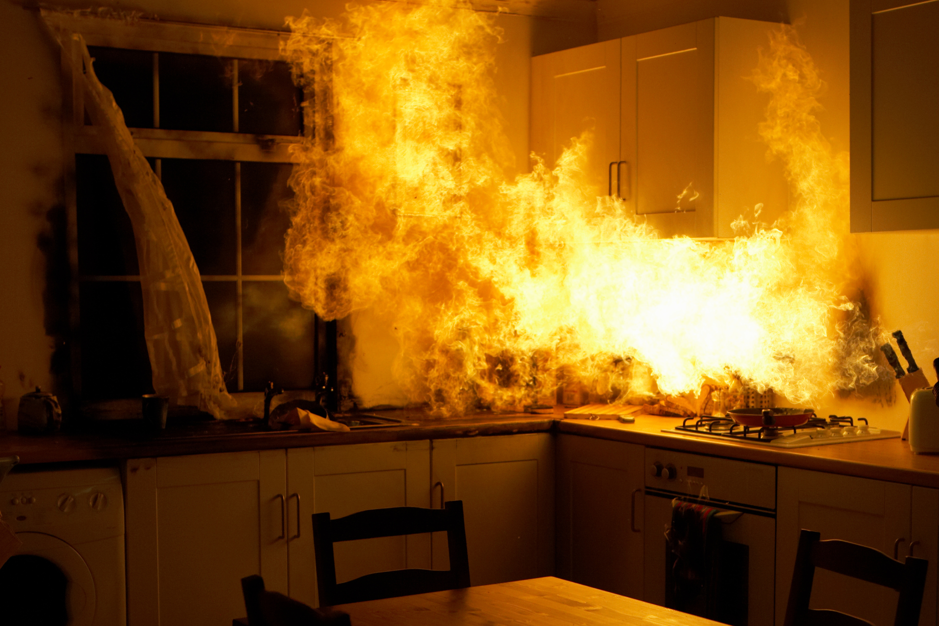 A kitchen with a lot of fire coming out of the stove.