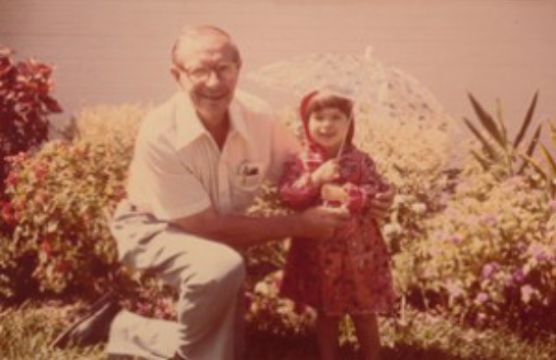 A man and a little girl are posing for a picture in a garden.