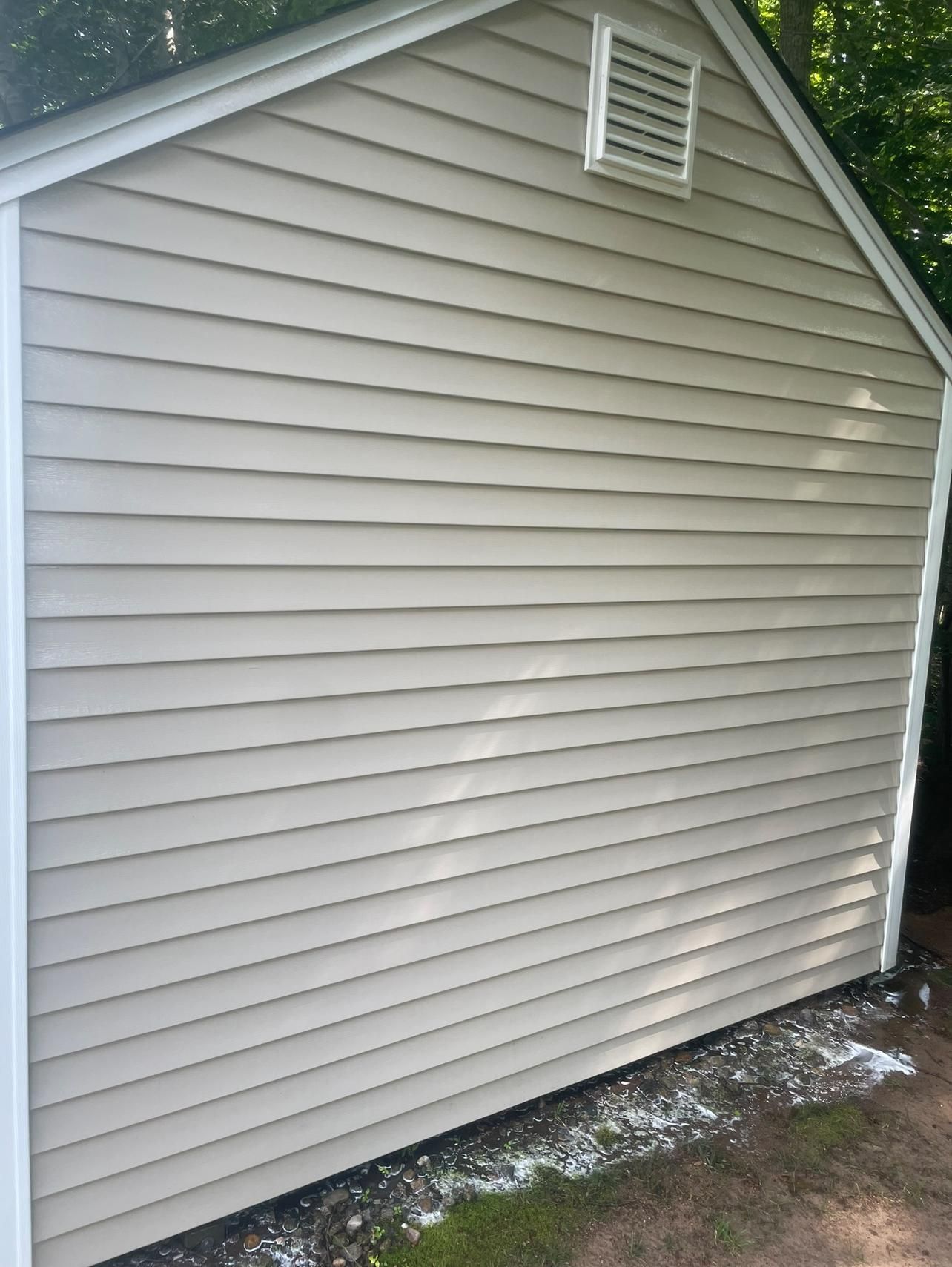 The side of a house with a white siding and a white trim.