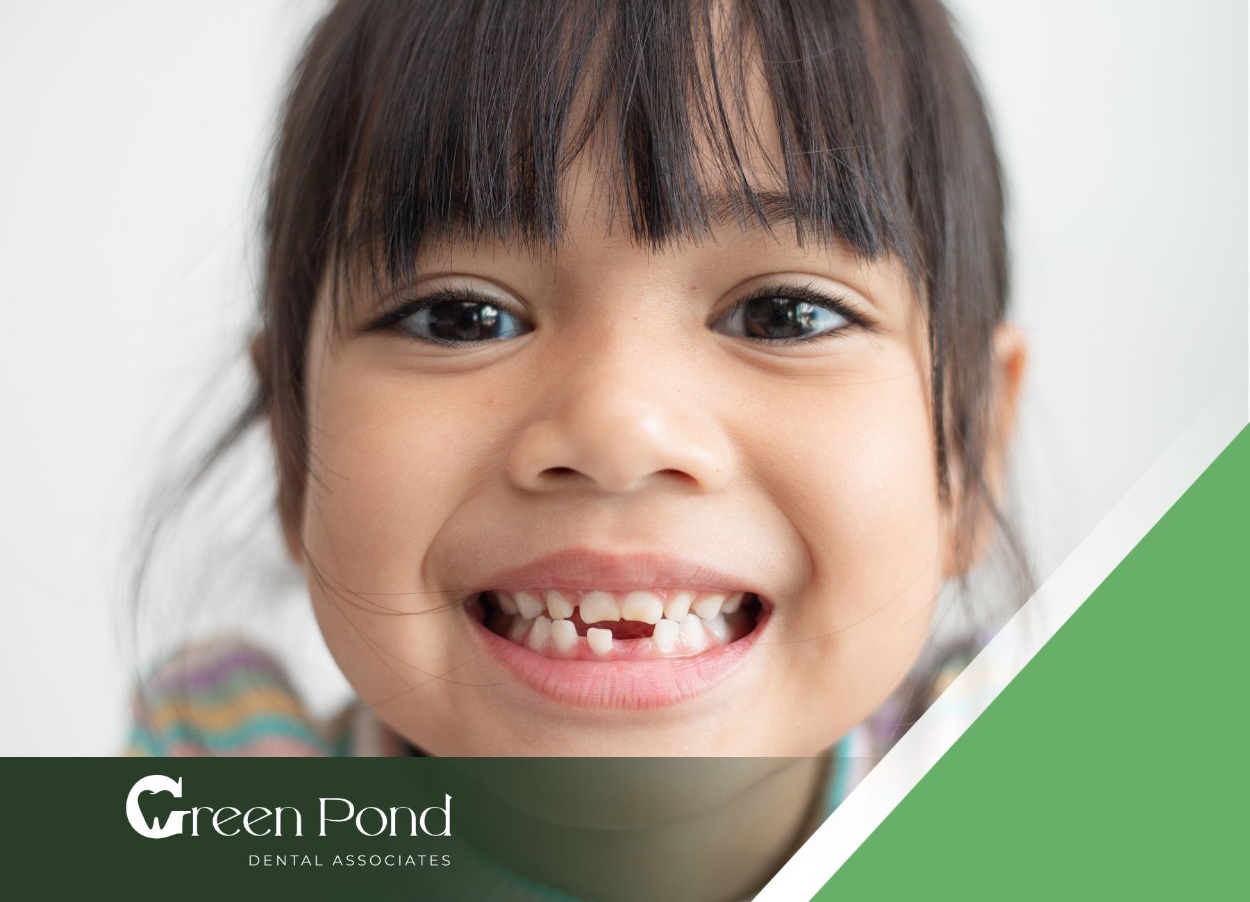 A little girl with missing teeth is smiling for the camera.