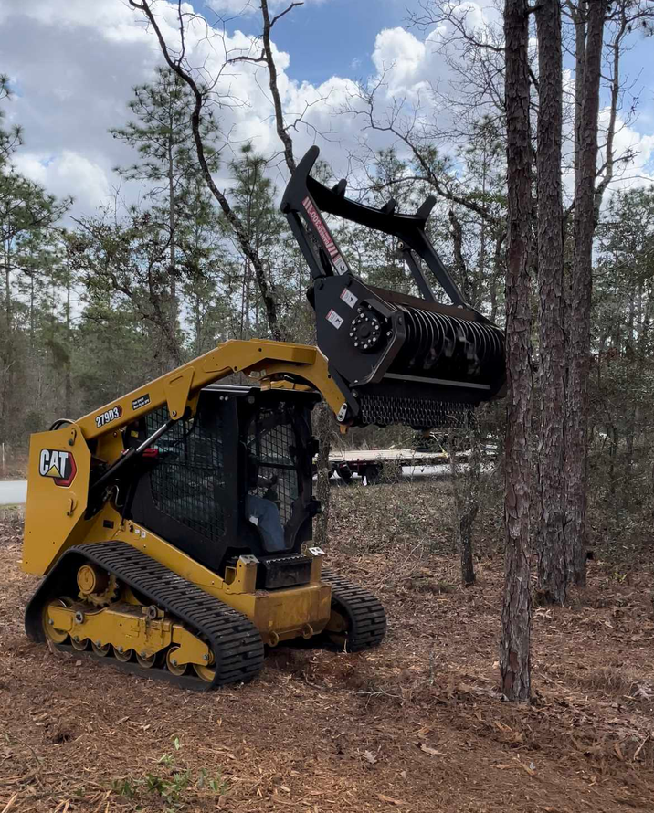 A bulldozer is cutting a tree in the woods.
