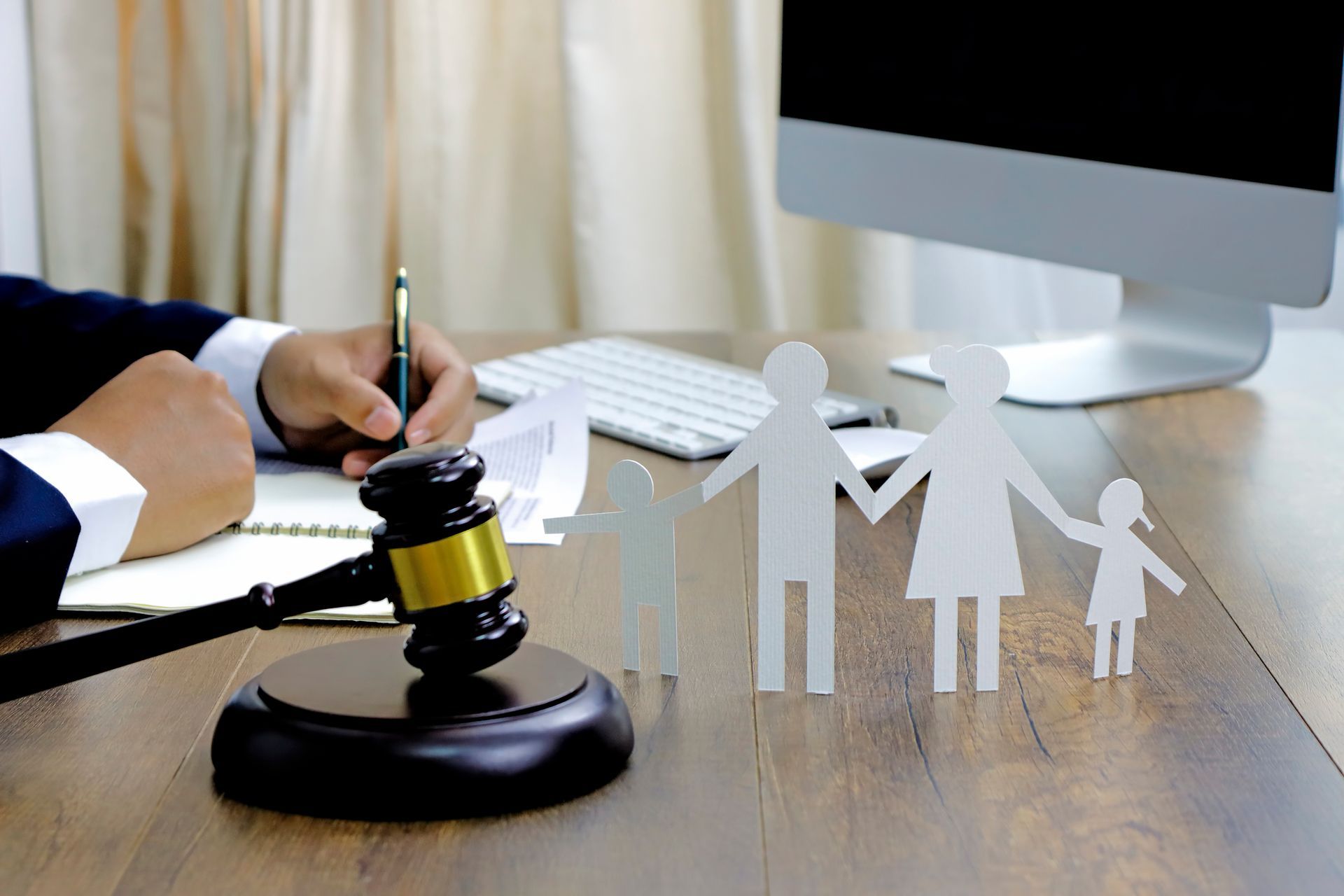 Child custody case attorney writing notes beside gavel and family cutout at legal office desk