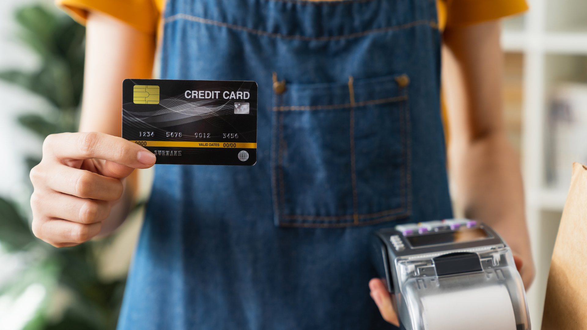 A woman is holding a credit card and paying with it.