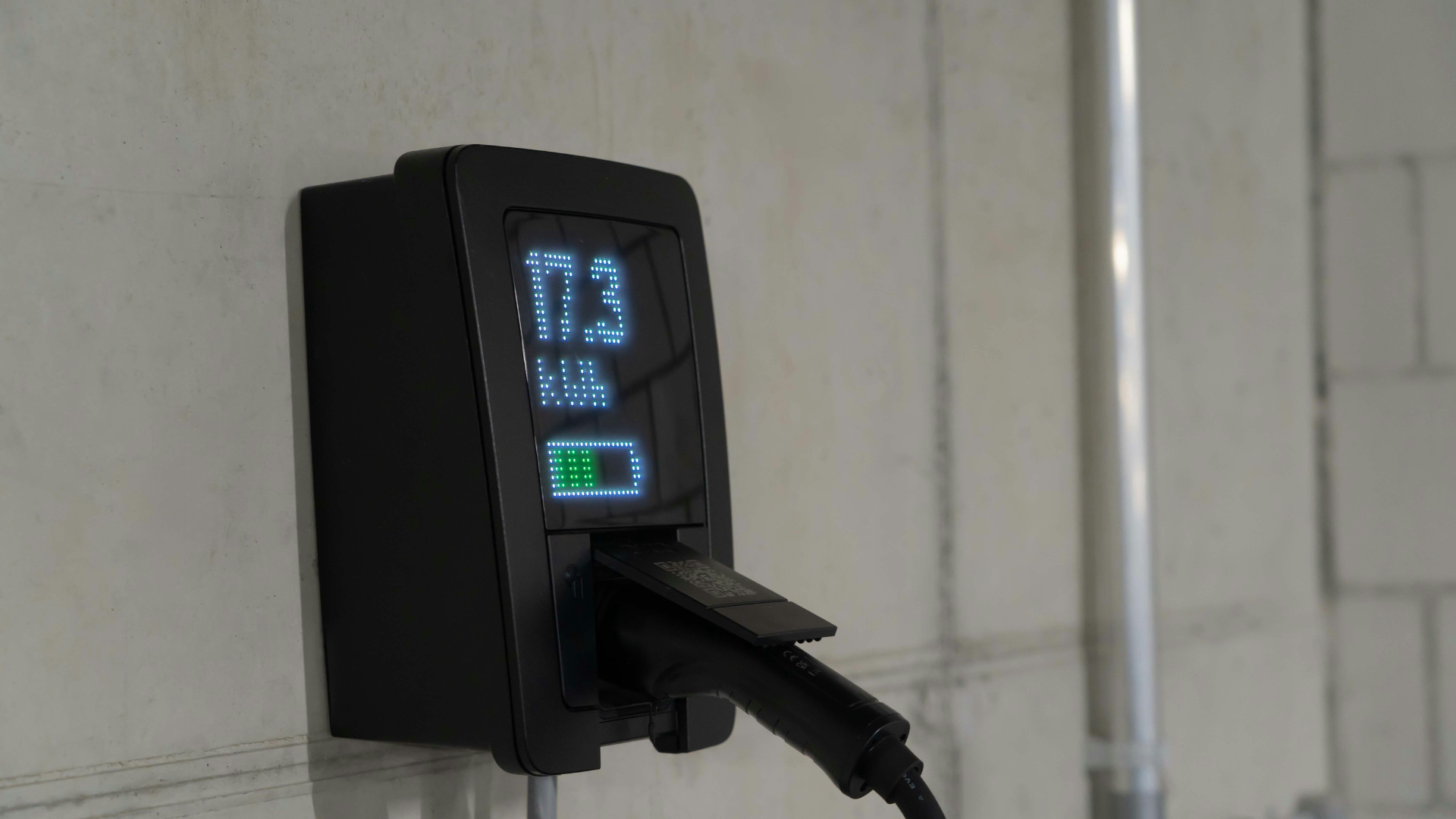 Black wall-mounted digital charger with a plugged-in cable displaying blue and green status lights