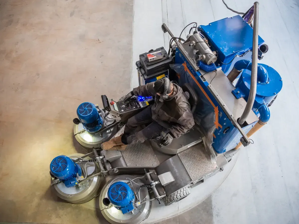 Betonschuurmachine dat een oude betonvloer aan het renoveren is