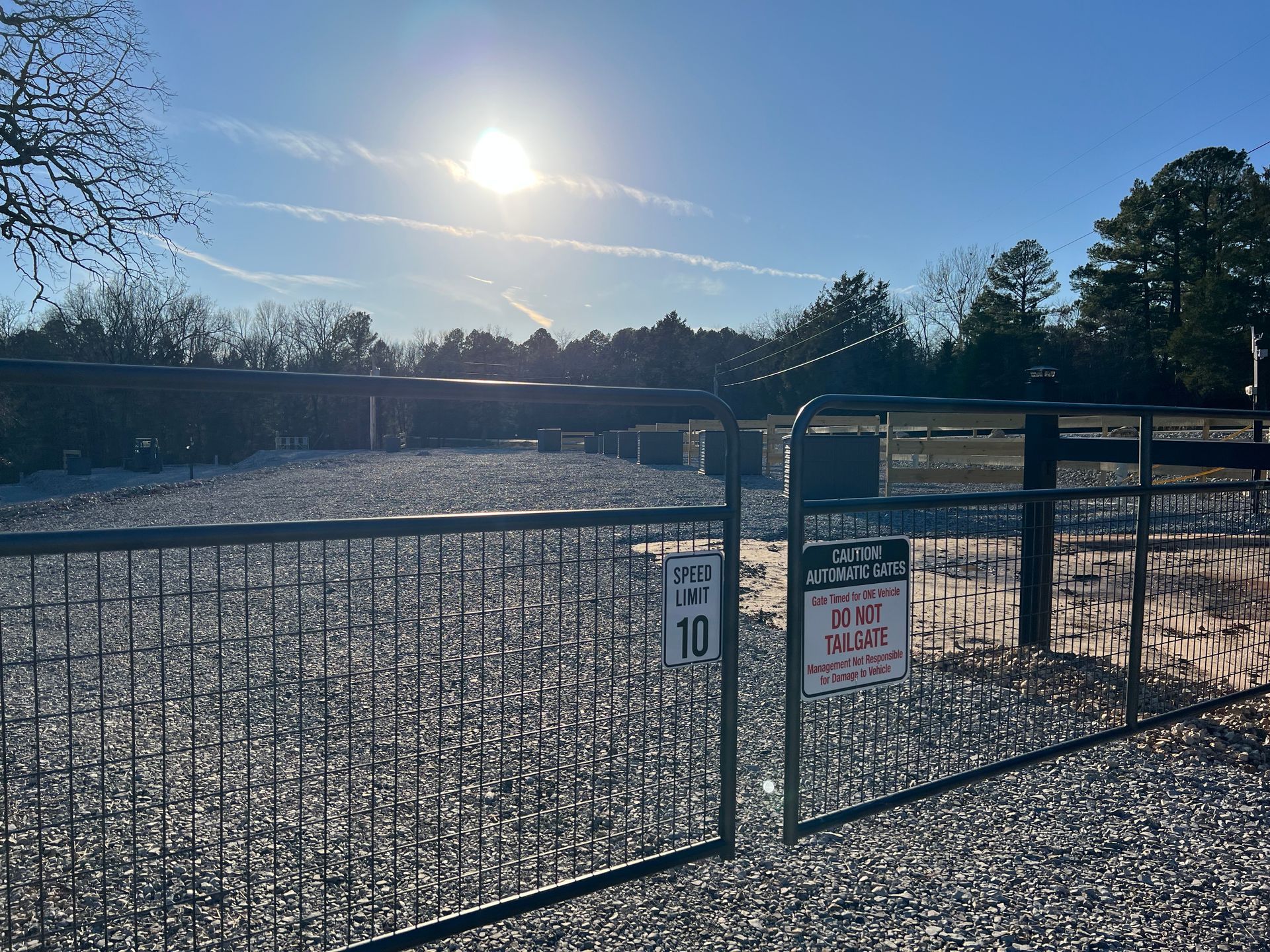 Snow-covered outdoor scene with trees and square dark planters against a bright blue sky.