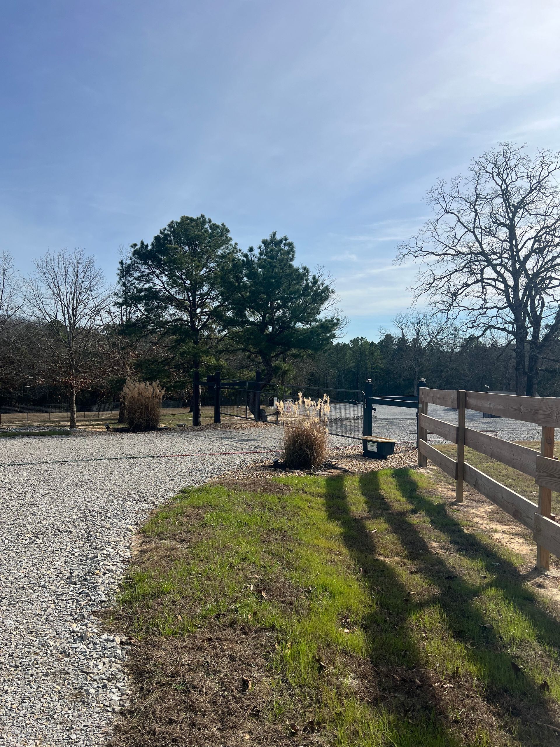 Trees frame a river with a small information kiosk and a parked white car in a fall landscape.