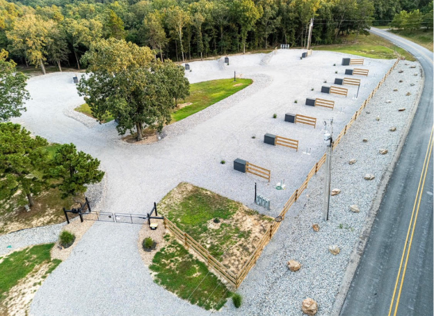 Trees frame a river with a small information kiosk and a parked white car in a fall landscape.