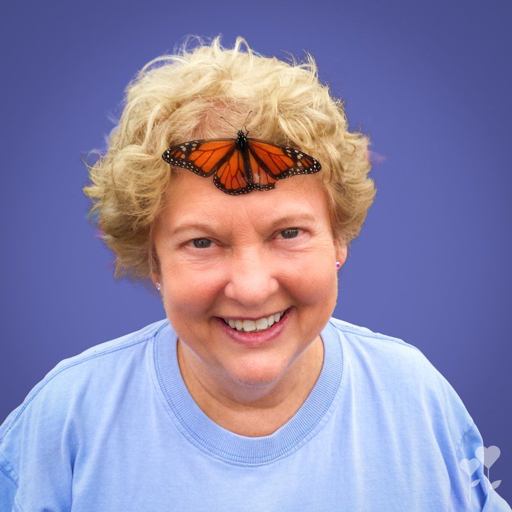 a woman in a blue shirt has a butterfly on her head