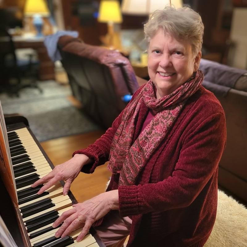 a woman in a red sweater is playing a piano