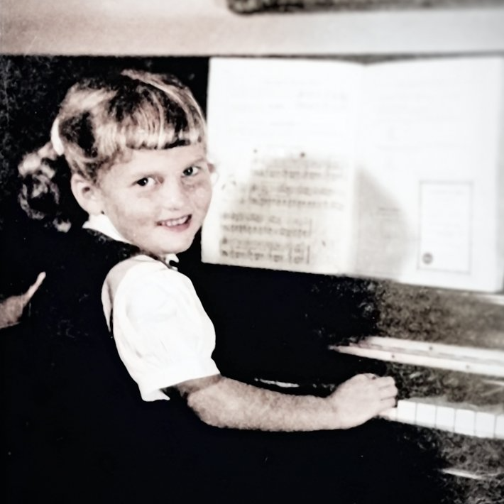a little girl is playing a piano in a black and white photo