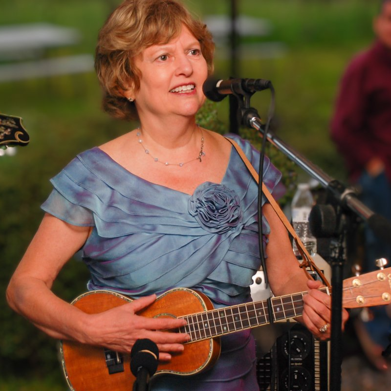 a woman in a blue dress is playing a guitar and singing into a microphone