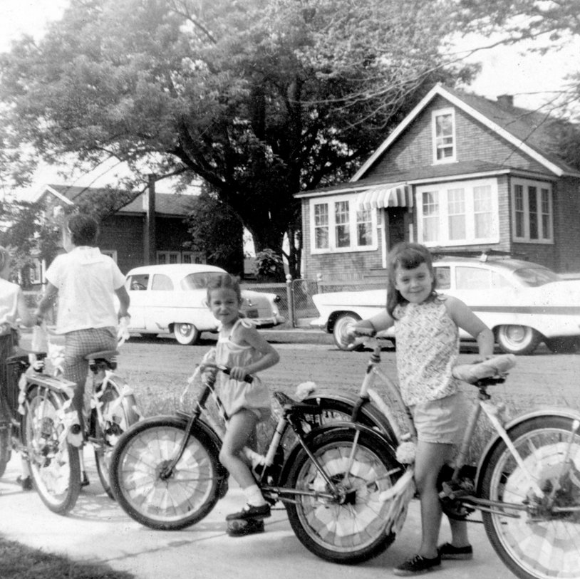 a black and white photo of three children standing next to their bikes