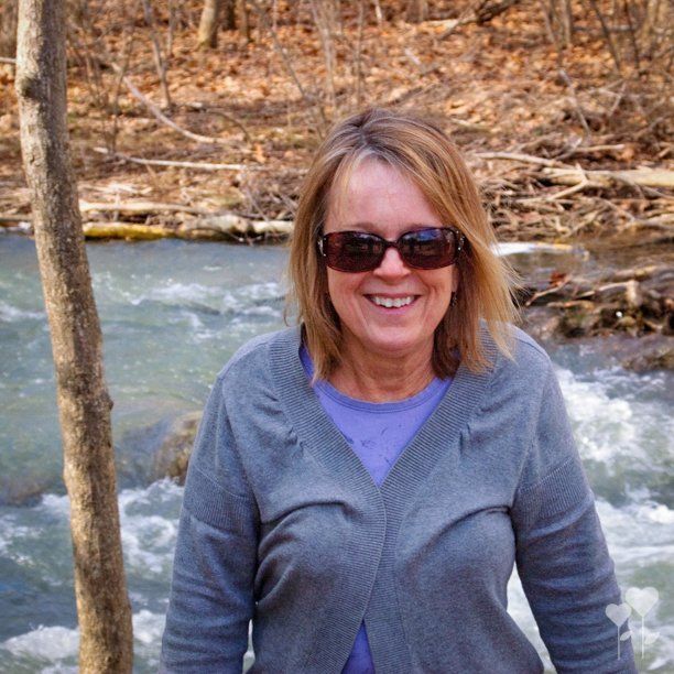 a woman wearing sunglasses stands in front of a river