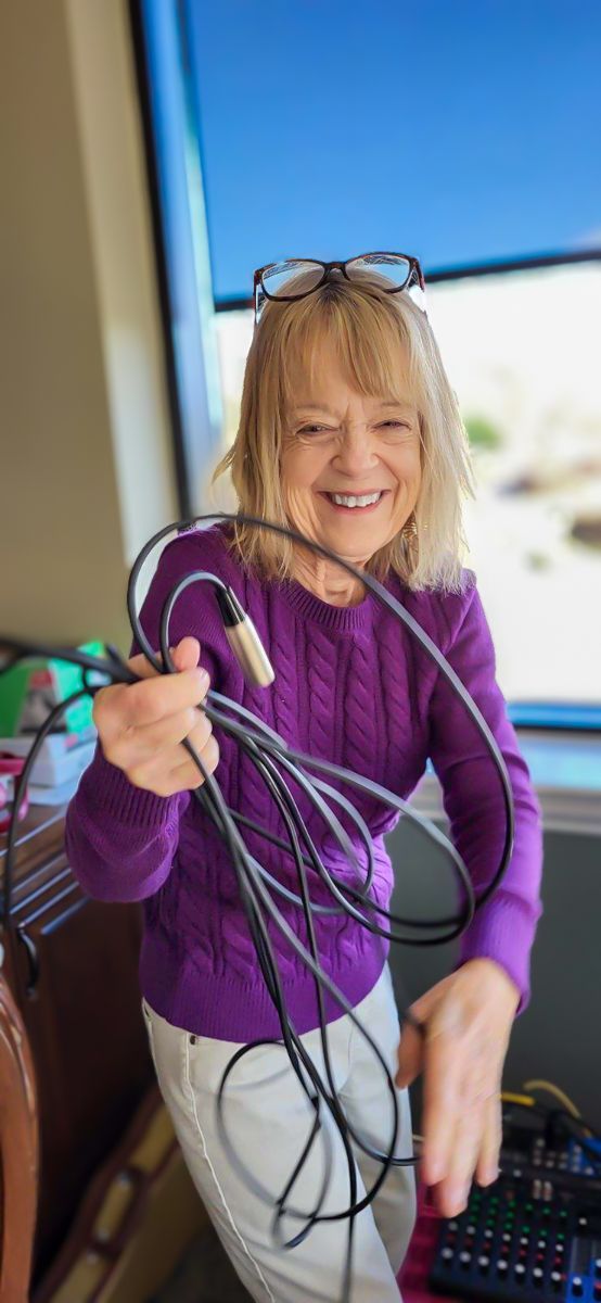 A woman in a purple sweater is holding a bunch of wires.