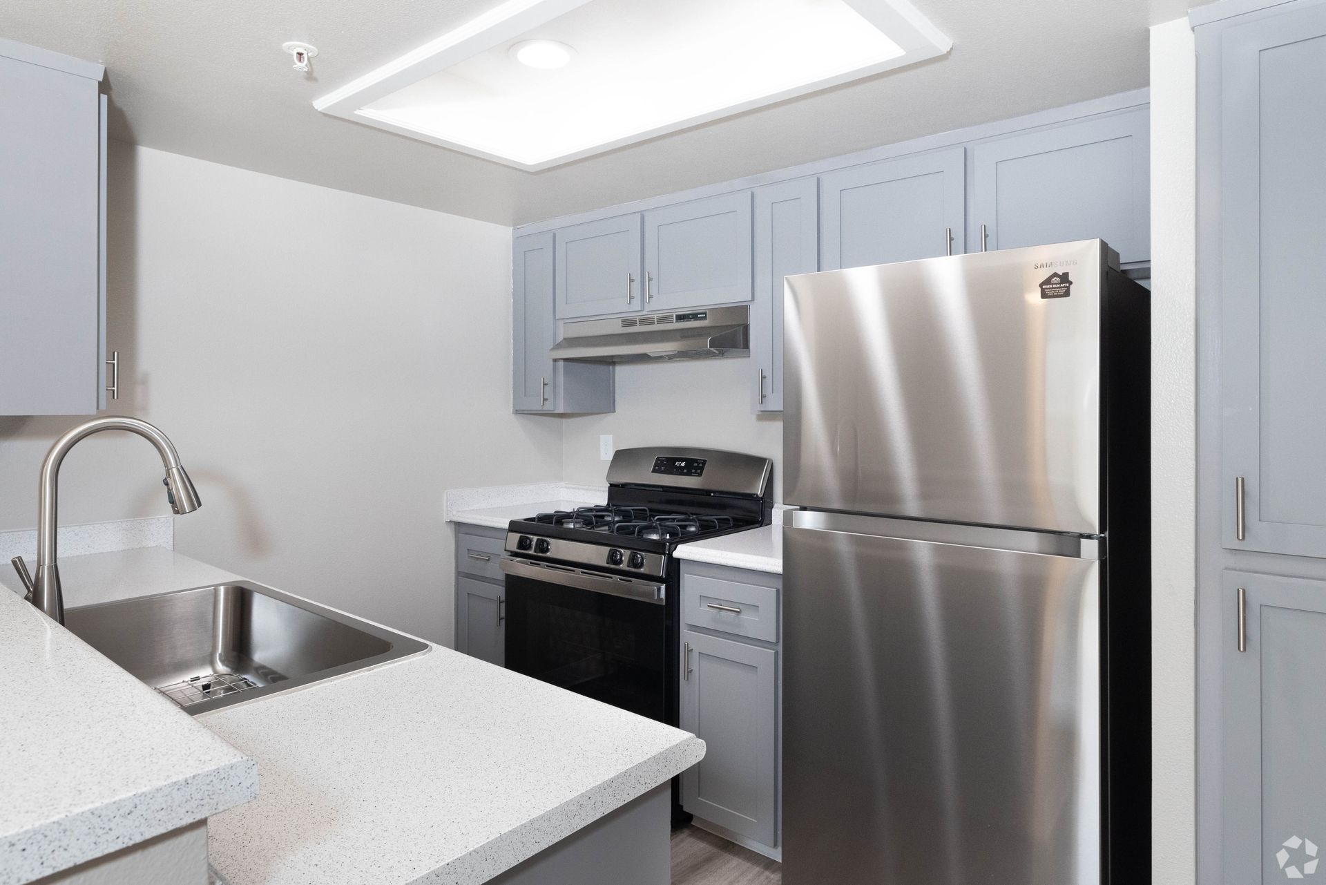 Kitchen with light blue cabinets, stainless steel appliances, and a white countertop.