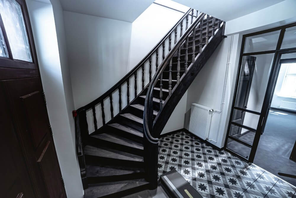 Staircase with gray finish and black and white floor tiles