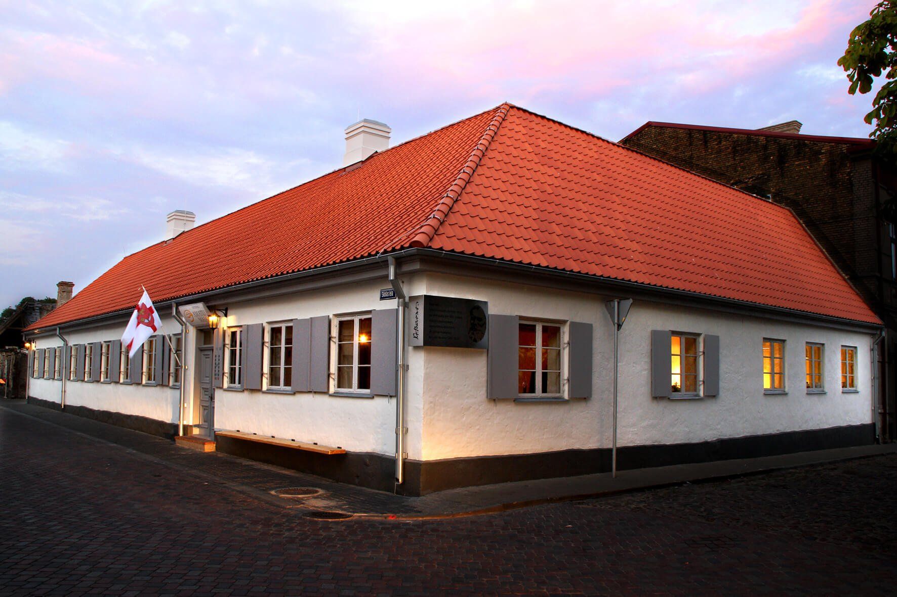 House with white walls, red roof and gray window frames