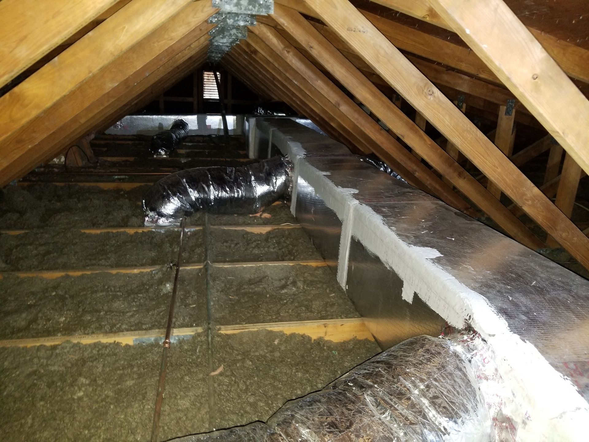 An attic with a lot of wooden beams and ducts