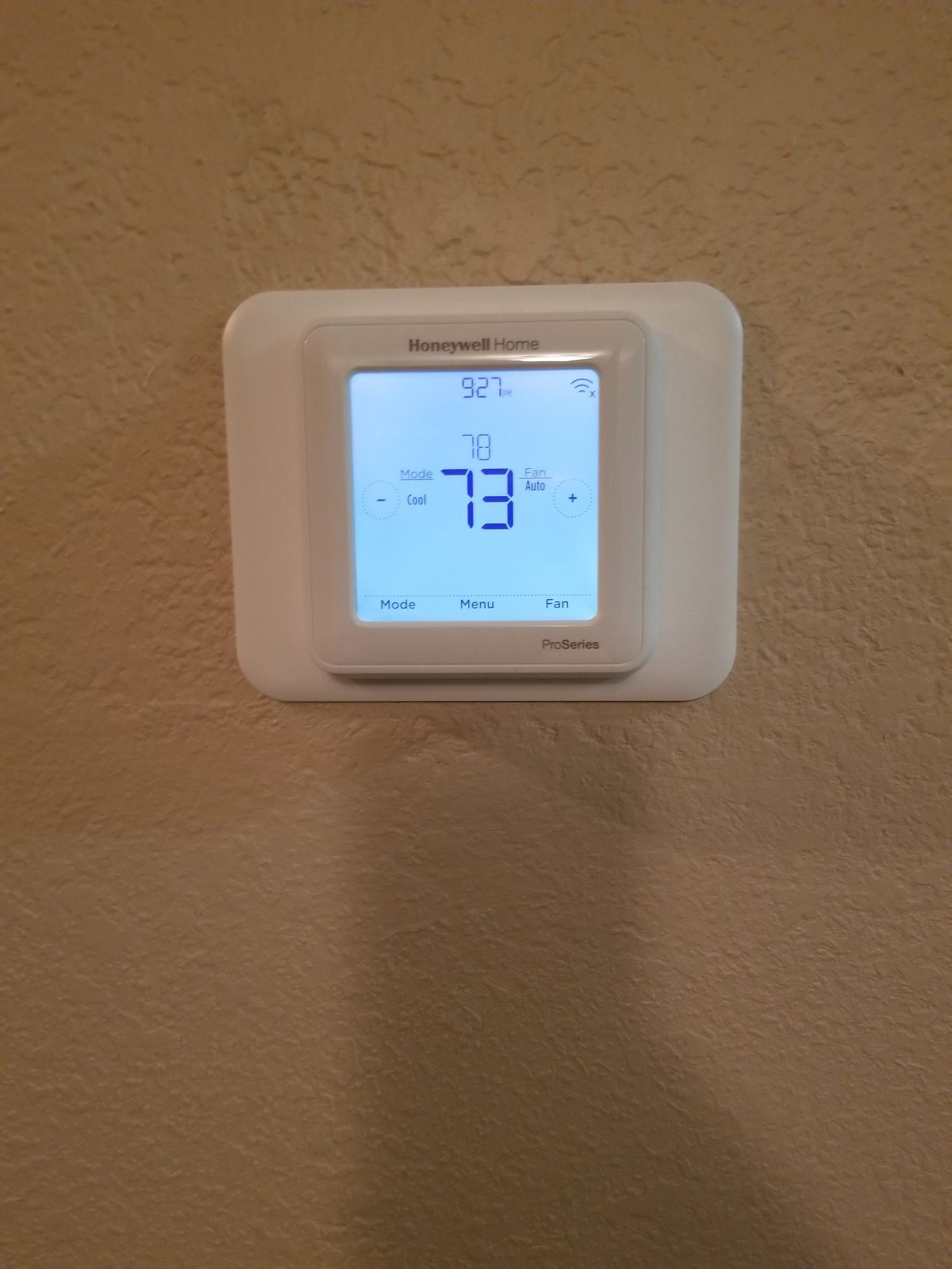 A white thermostat is mounted on a wall.