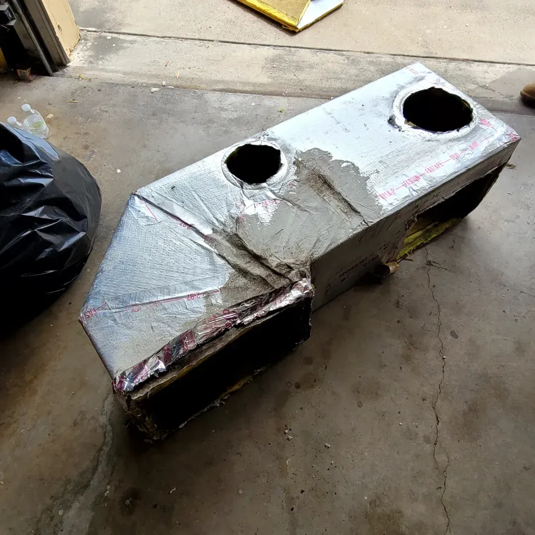 Two air conditioners are sitting outside of a house.